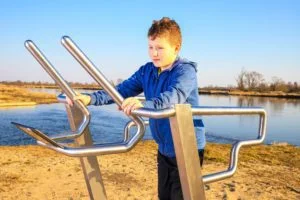smiling little boy is exercising on an outdoor treadmill